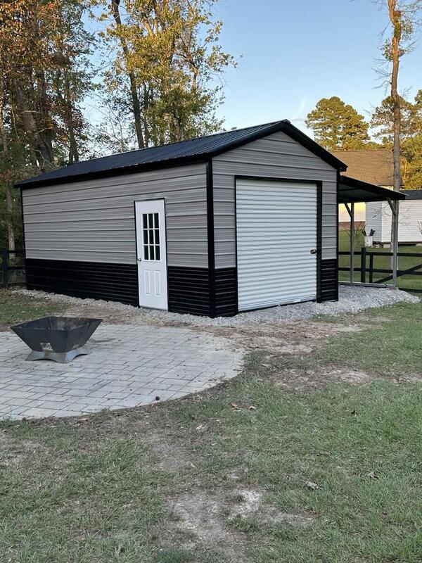 Gray metal garage with black lower panels, a roll-up door, a walk-in door, and an open lean-to on the side