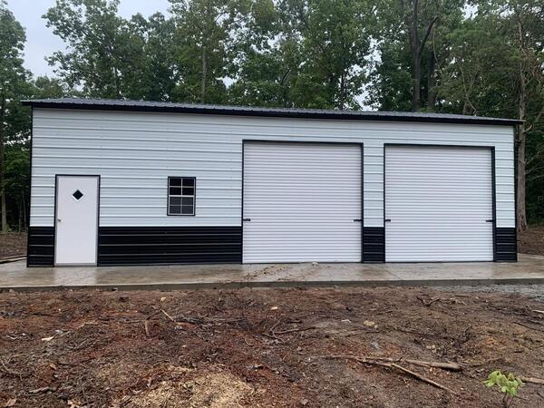 Front of a white and black metal garage with two roll-up doors, a walk-in door, and a window