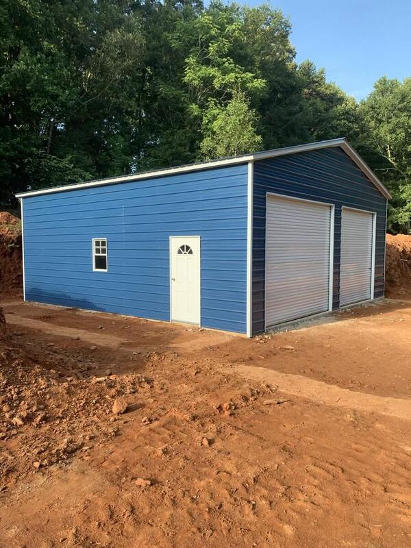 Blue metal garage with white trim, two roll-up doors, a walk-in door, and a window