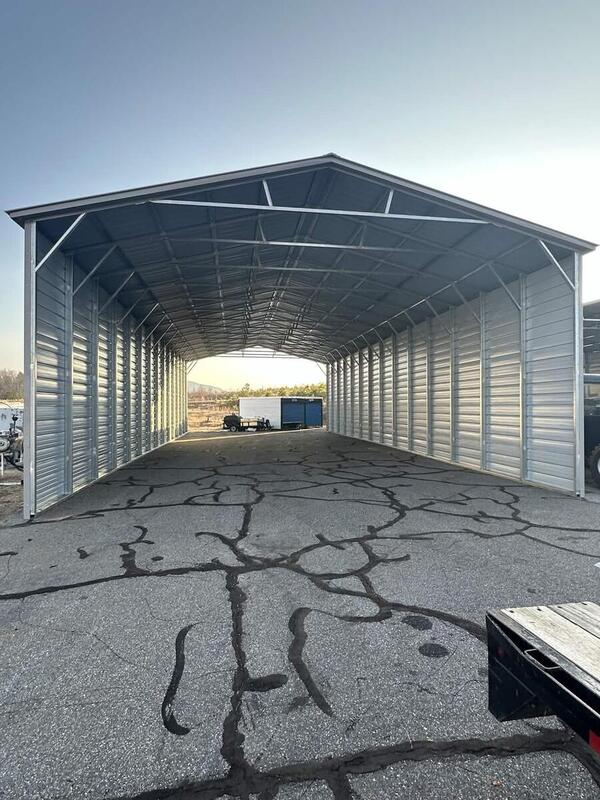 Tall metal cover with a vertical roof, closed sides, and open ends, on asphalt